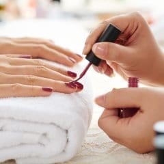 Image of Side view of manicurist applying nail polish