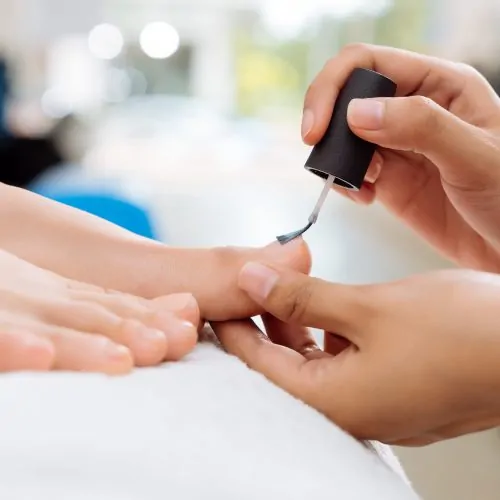 Image of Close-up of pedicurist applying nail polish to the toenails, selective focus