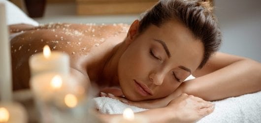 Bliss Spa Package Young woman relaxing in a spa salon with exfoliating scrub on her back.