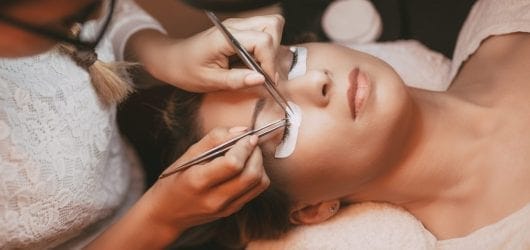 Procedure Eyelash Extensions Image of a beautician applying fake eyelash extensions to a woman